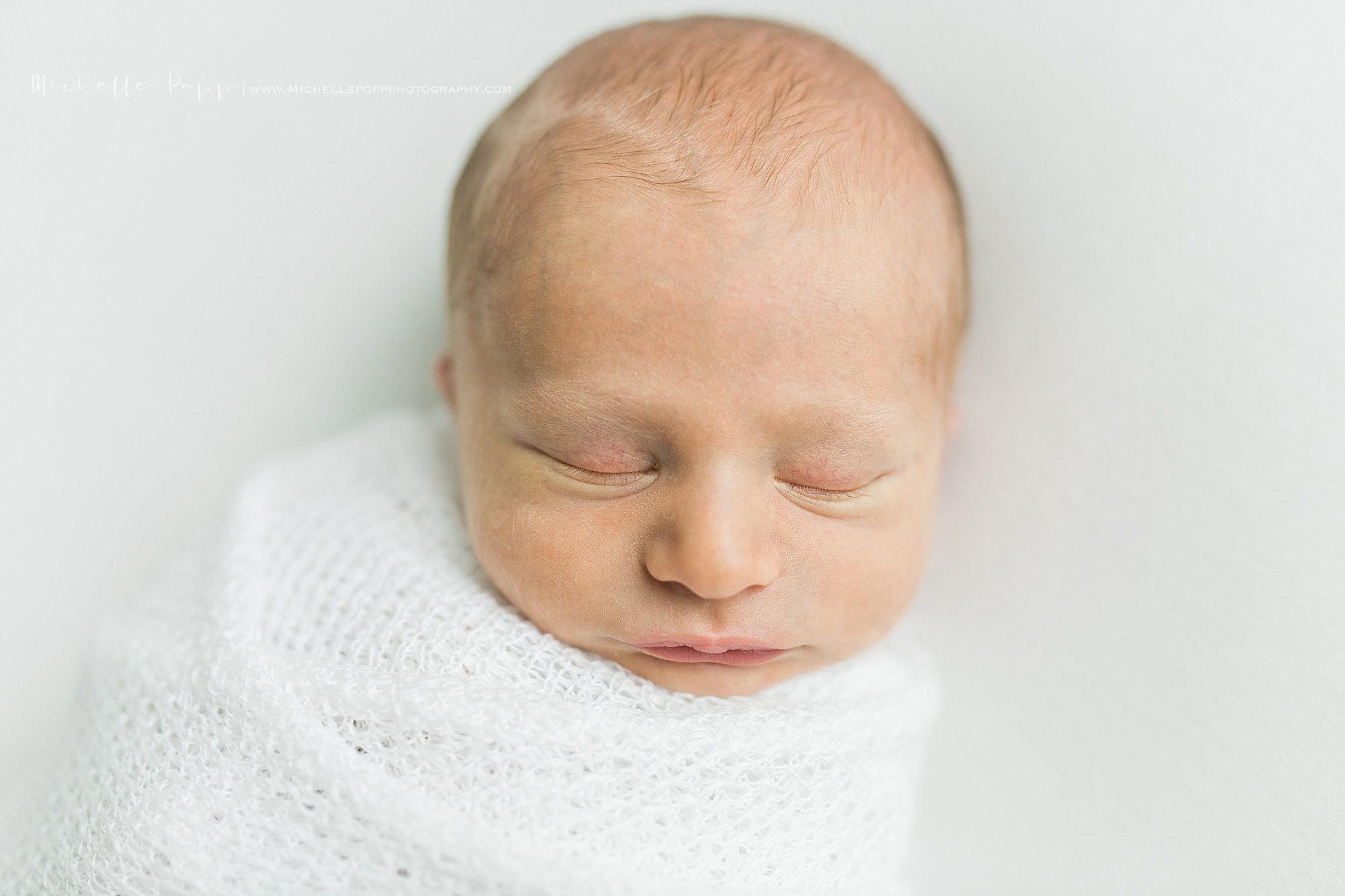 Closeup of baby in white swaddling 