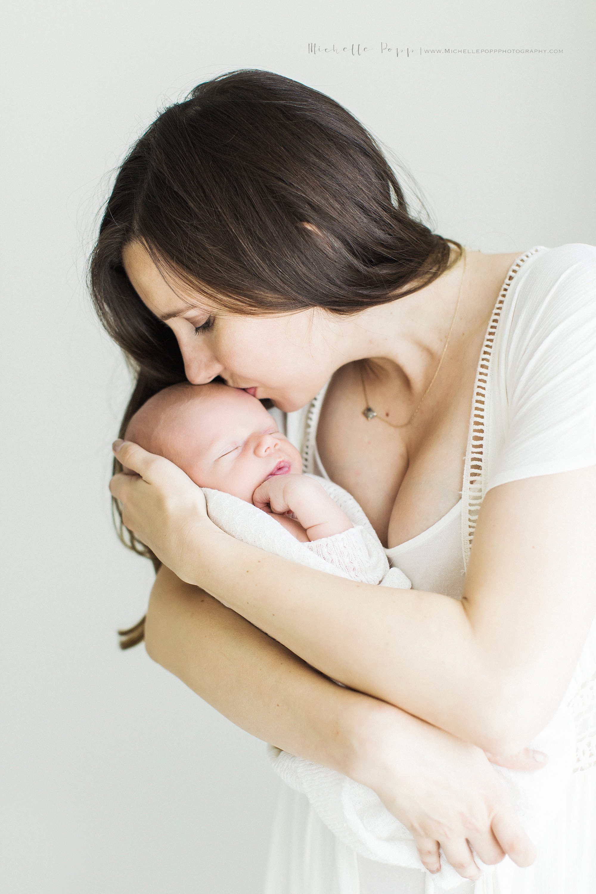 Mom kissing sleeping newborn baby boy