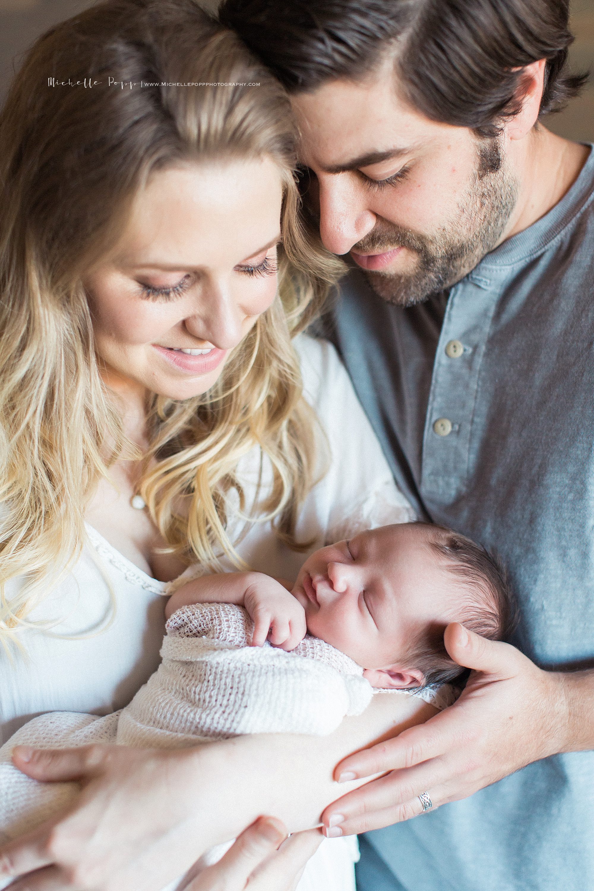 mom and dad smiling at newborn baby 