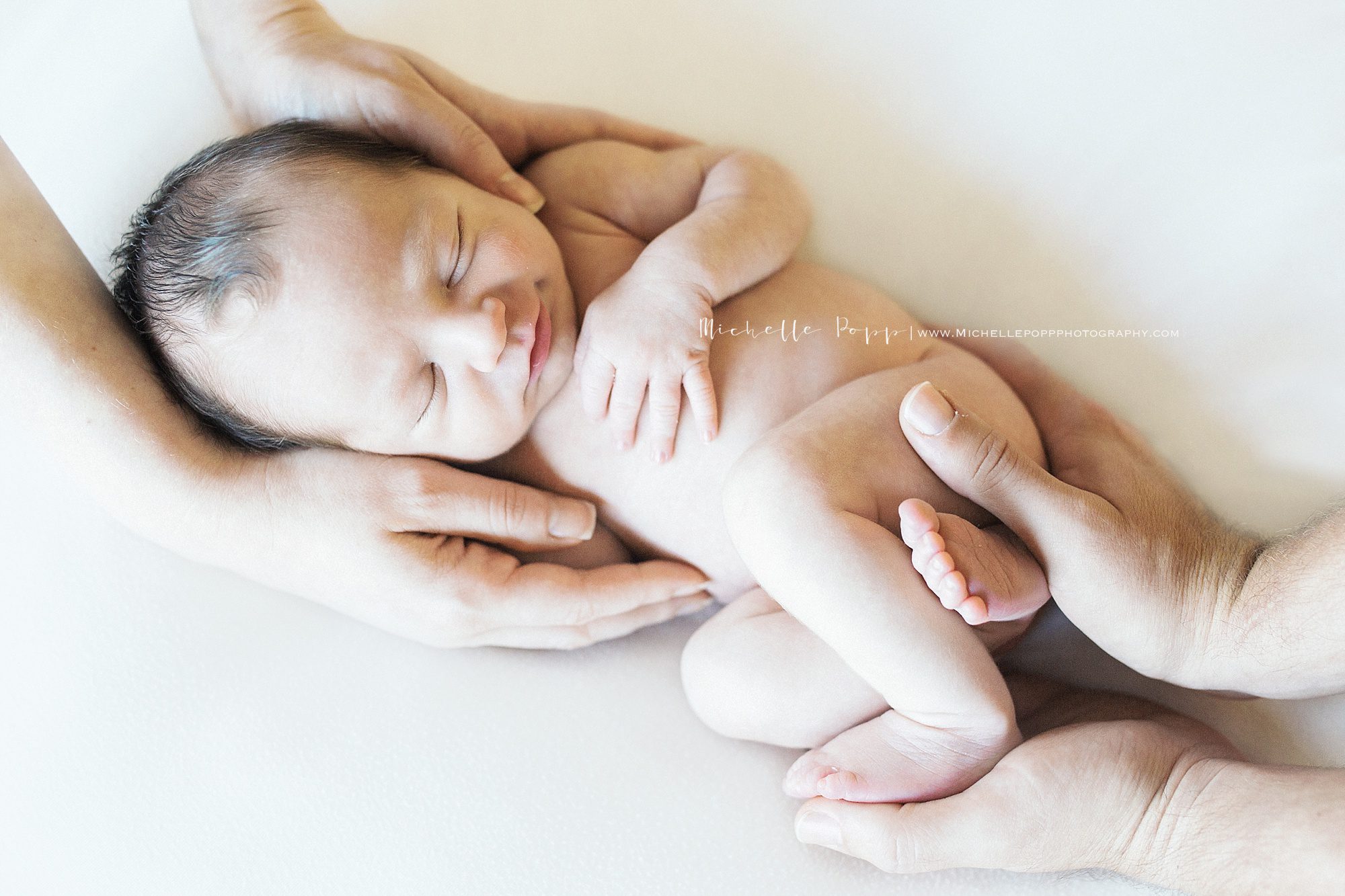 mom and dads hand holding newborn baby