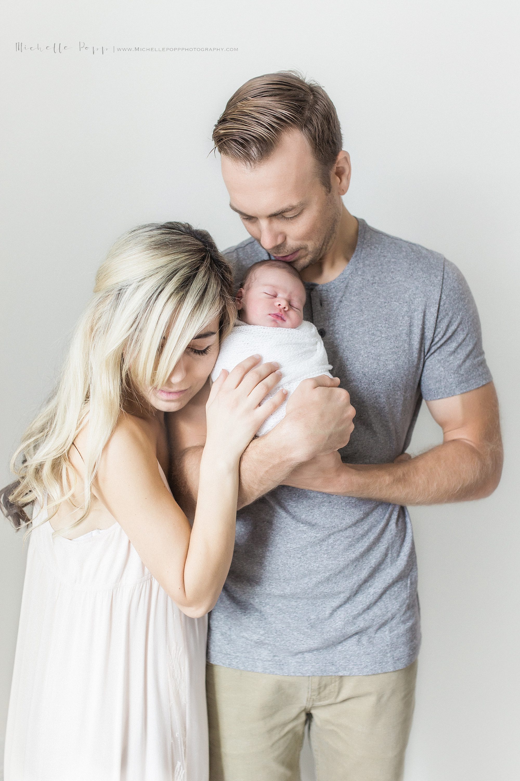 Dad kissing babies head and mom nuzzling baby