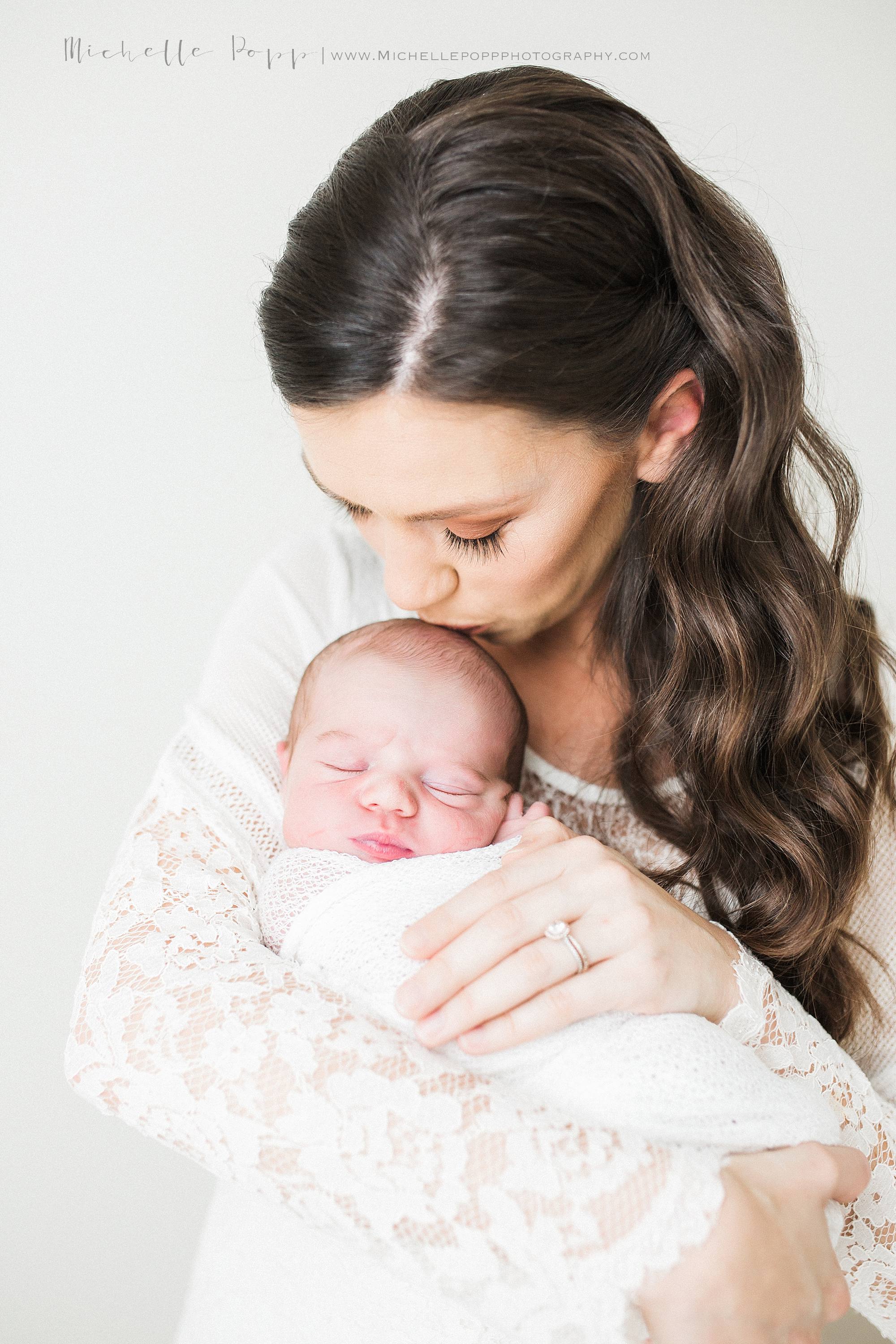 close up of Mom in all white lace dress kissing babies head