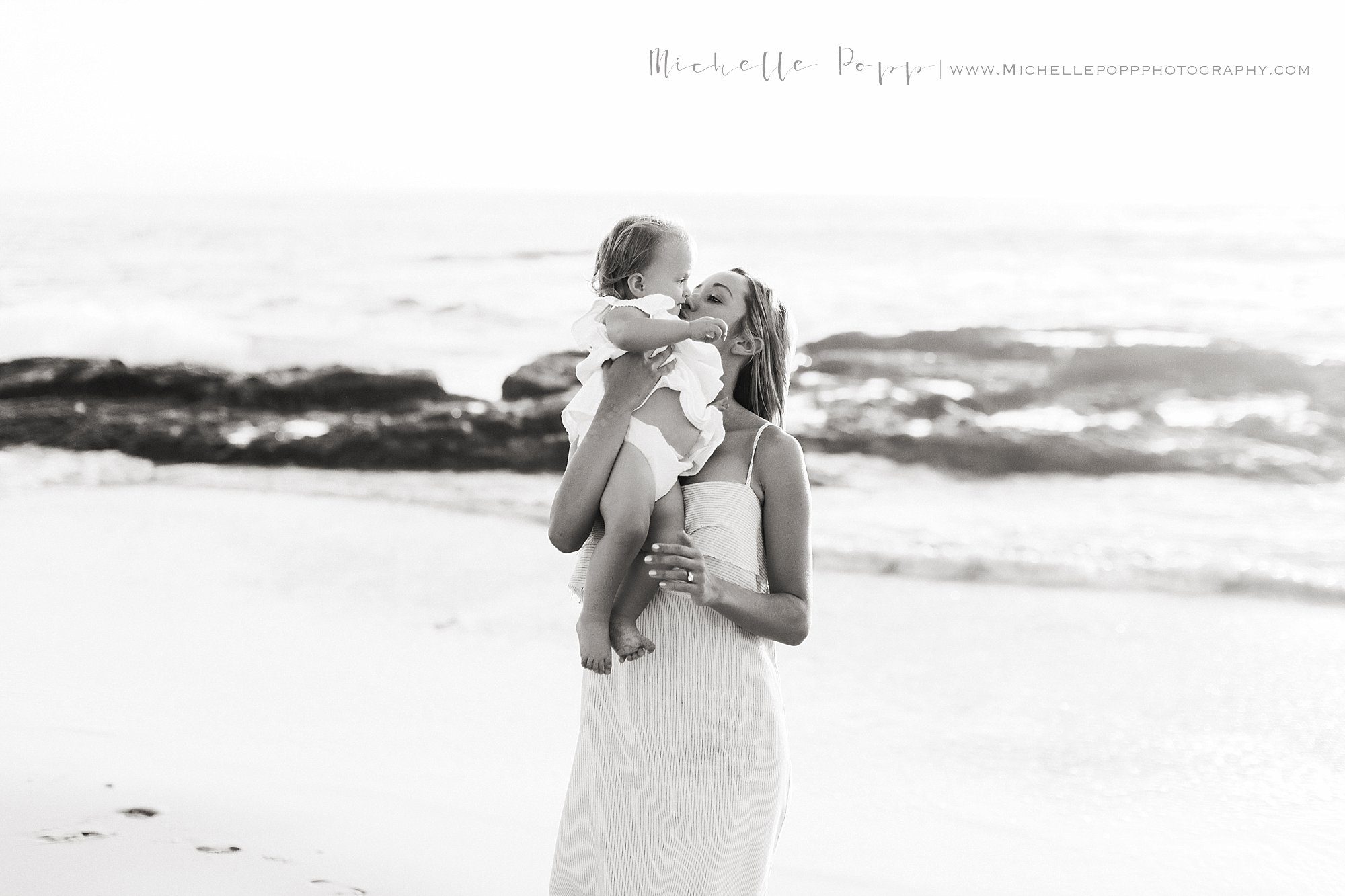black & white photo of mom holding and kissing baby