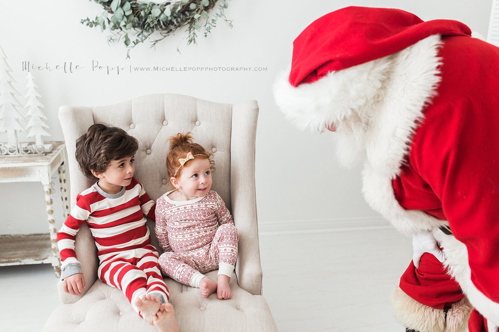 Santa looking at boy and girl sitting on chair