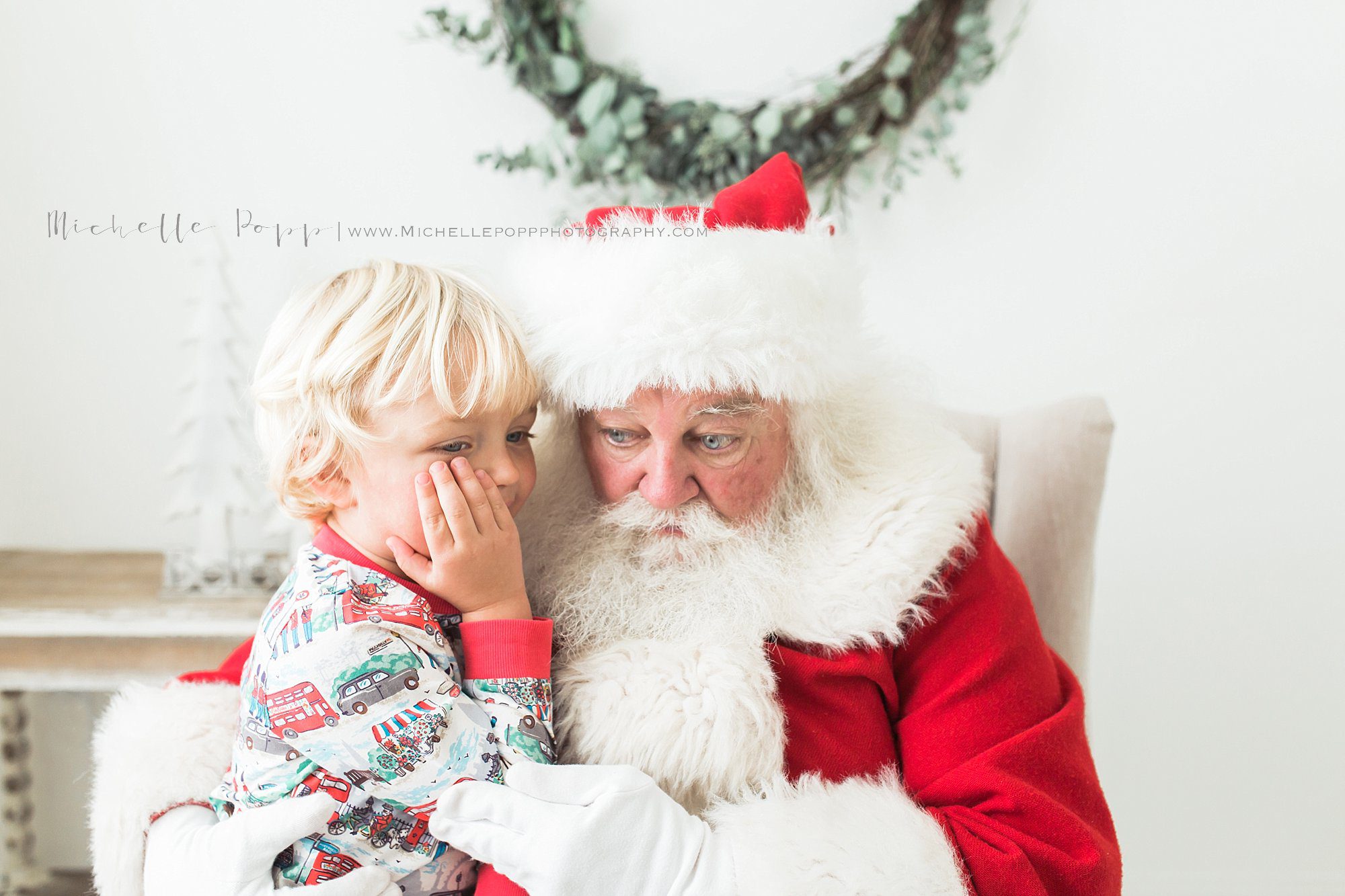 little boy whispering into Santa's ear