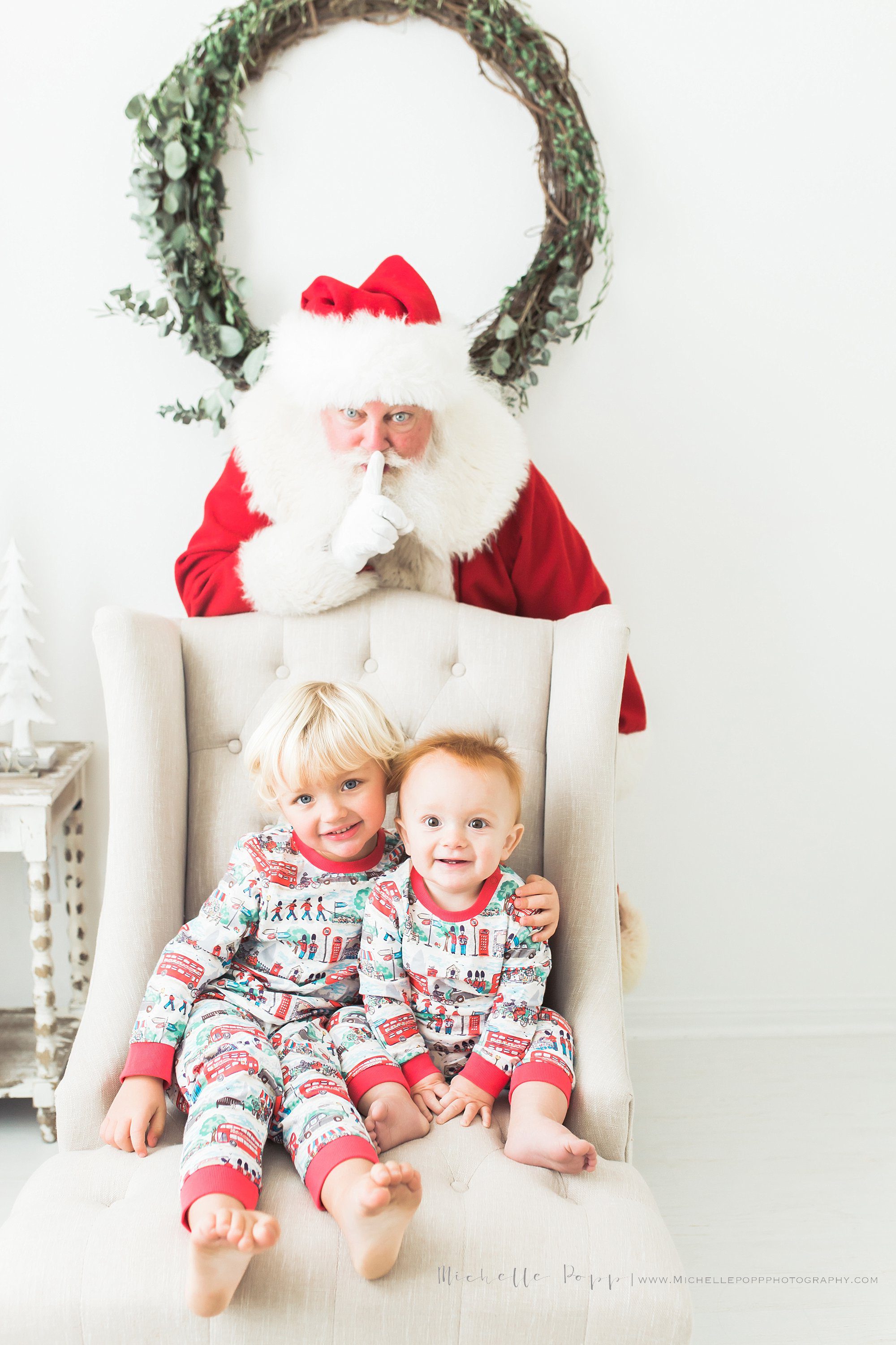 two little boys smiling with Santa behind them