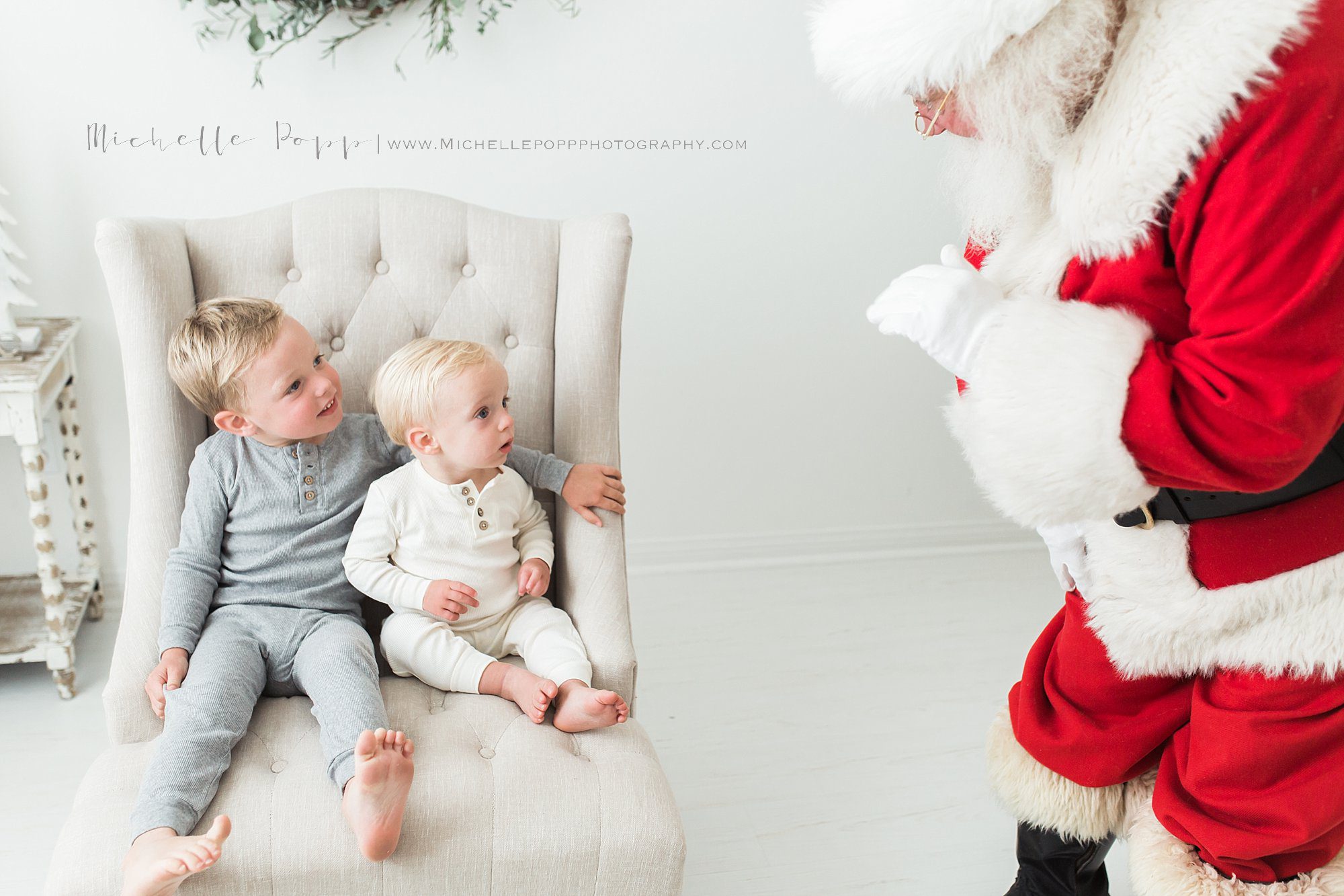 Santa waving to two little boys sitting on chair