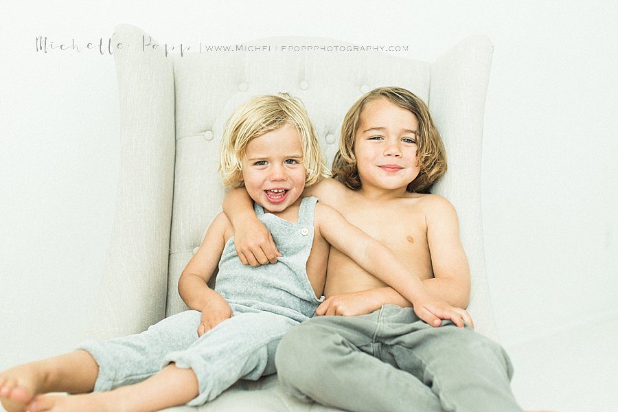 toddler boys on chair with arms around each other