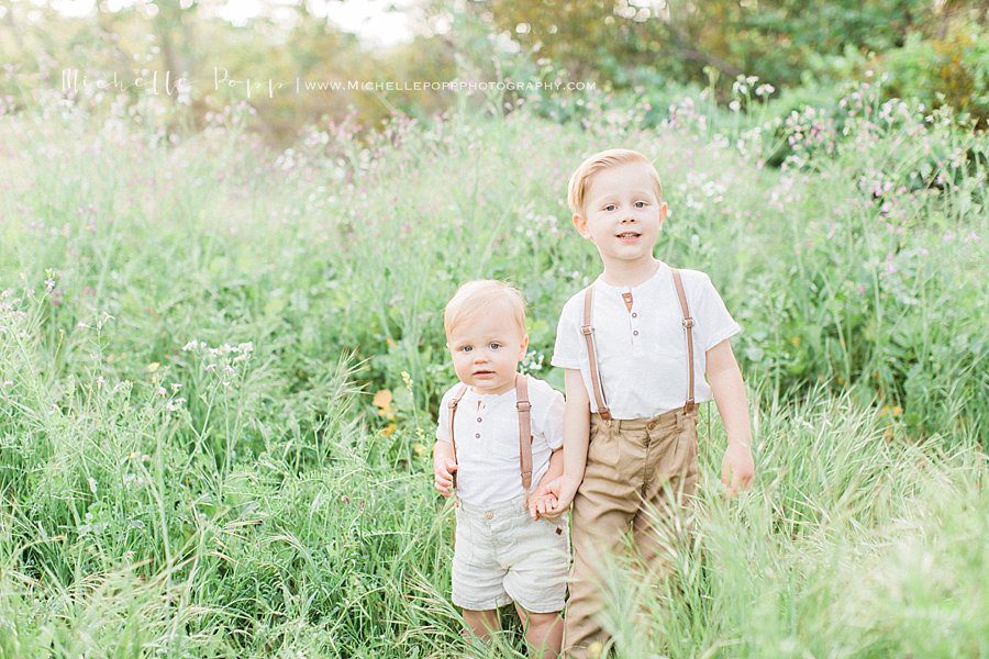 two children walking through the tall san diego grass during portrait session
