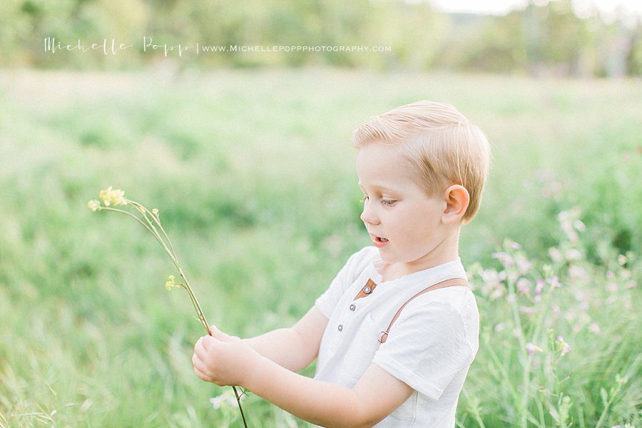 child playing with wildflowers during outdoor child photoshoot