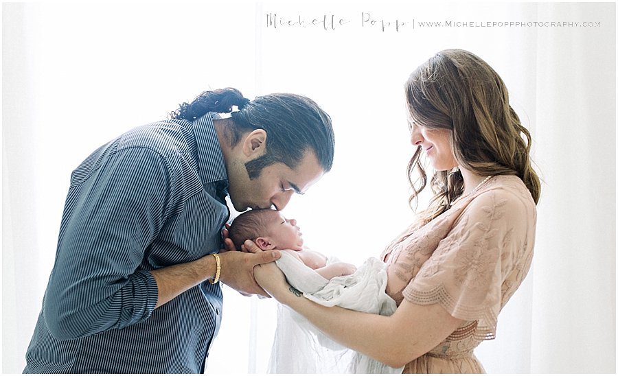 father kissing his son's forehead during a newborn portrait session