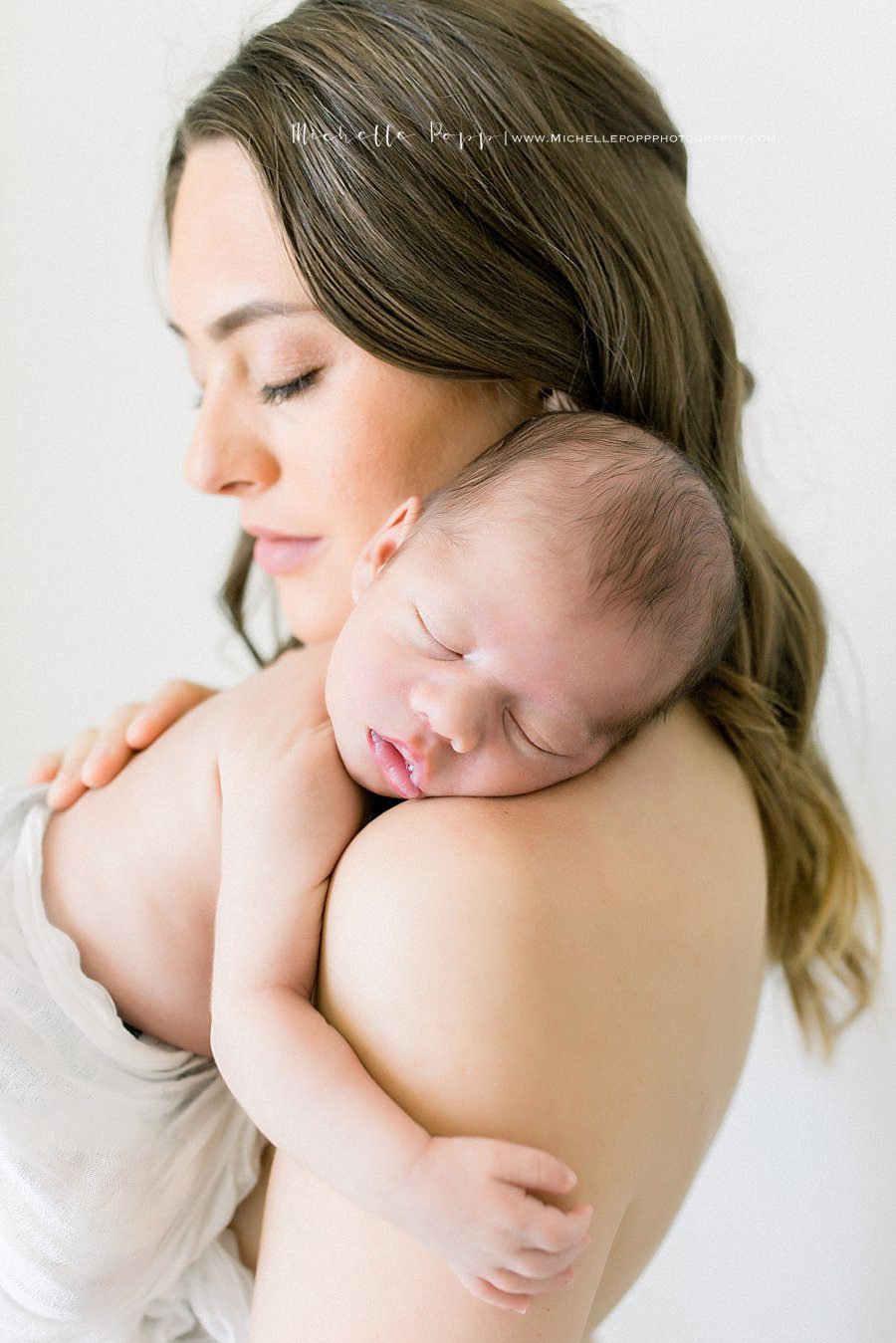 mother gently holds her newborn baby during the newborn photography shoot