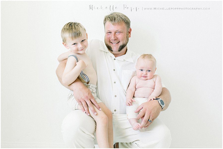 father smiling and holding his happy children during a family photography session