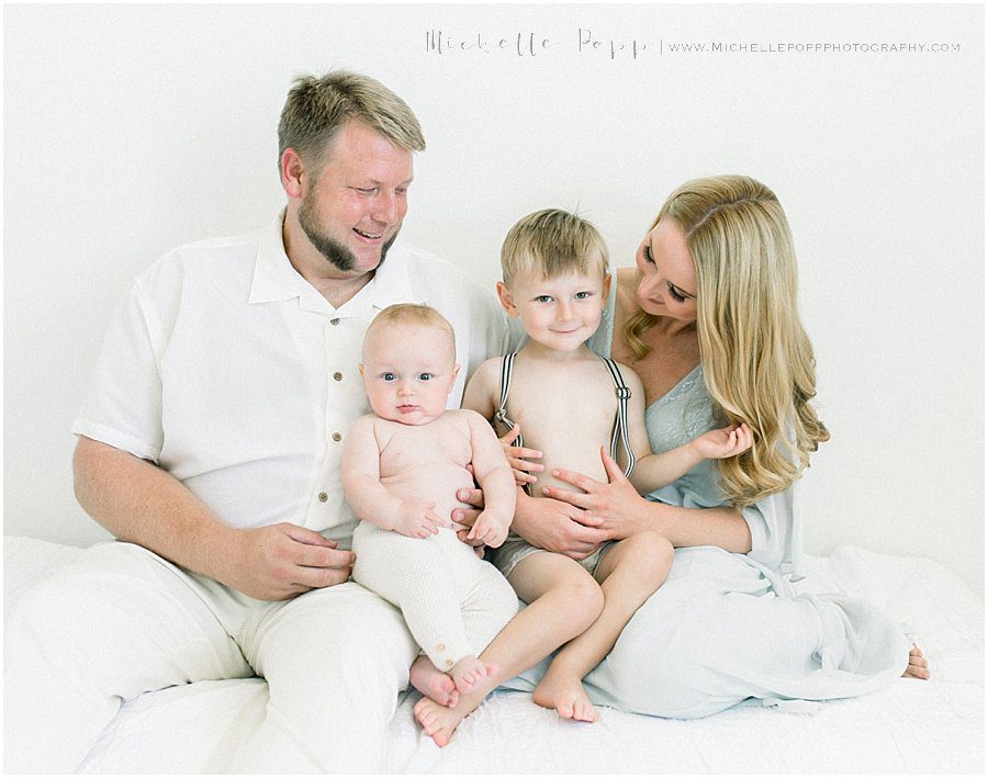 smiling family have natural baby photography pictures taken in a San Diego studio