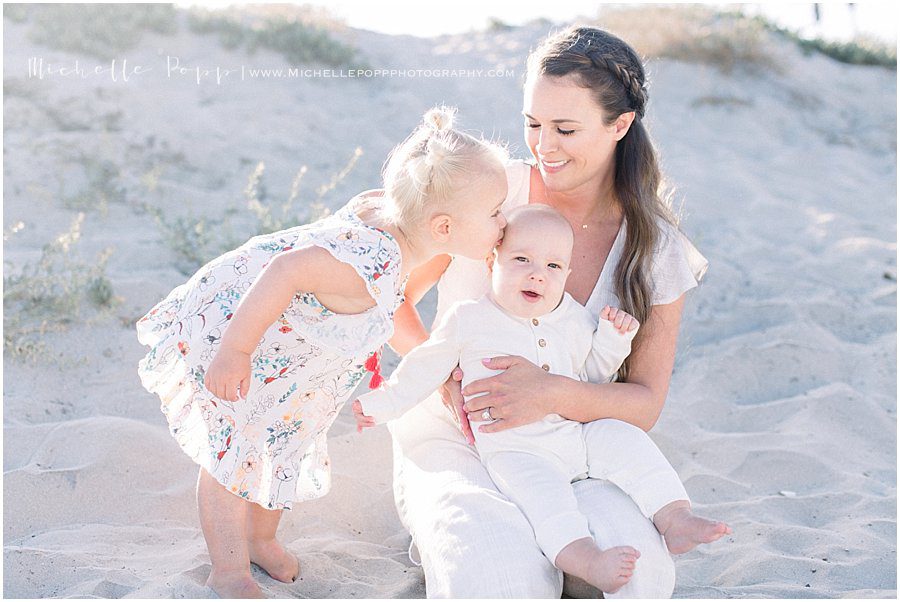 smiling mom, daughter, and baby girl during family beach photo session