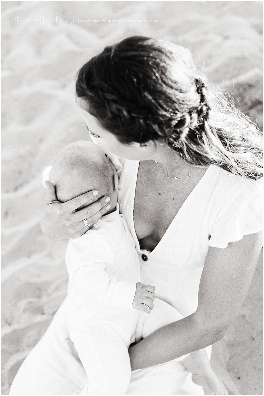 black and white picture of a mother holding her baby on the beach