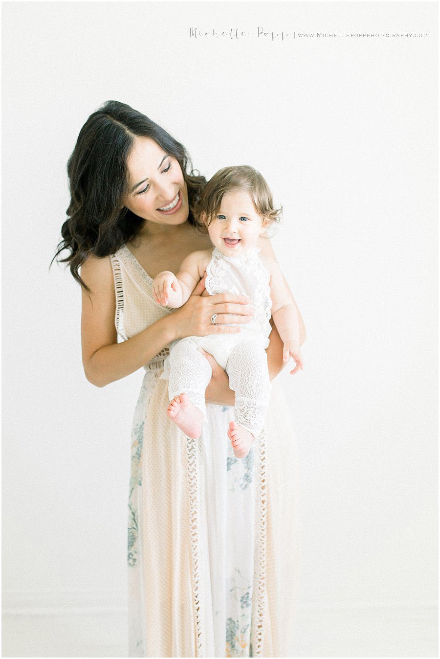 a mother holds her baby girl and smiles down on her during a San Diego photoshoot