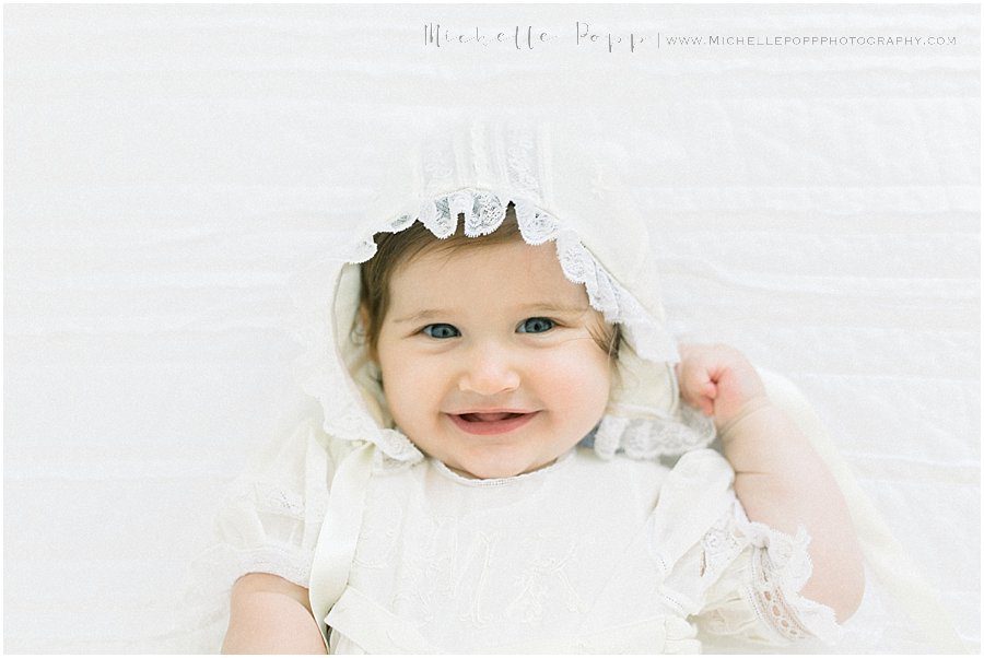 a baby girl with blue eyes smiles while looking at the camera