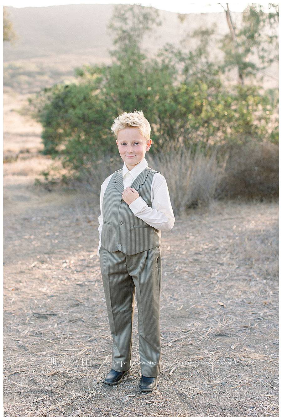 boy in tuxedo smiling at camera in field