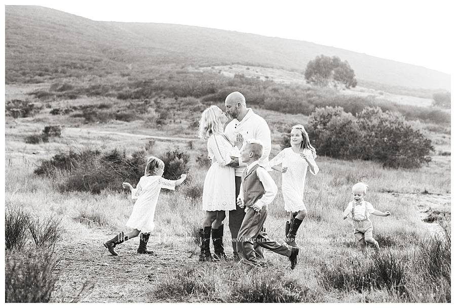 black and white of family in field with children running around parents