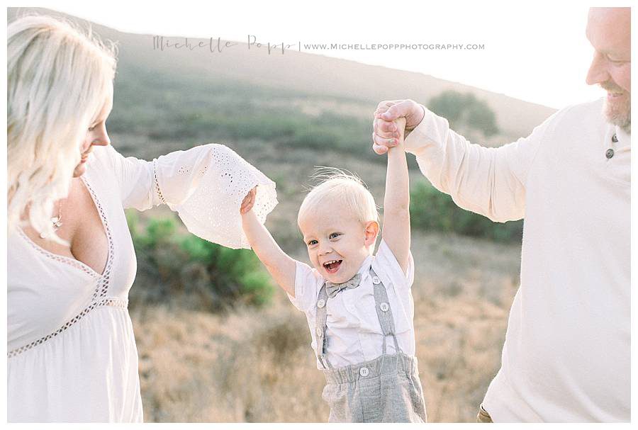 mom and dad swinging little boy by the arms