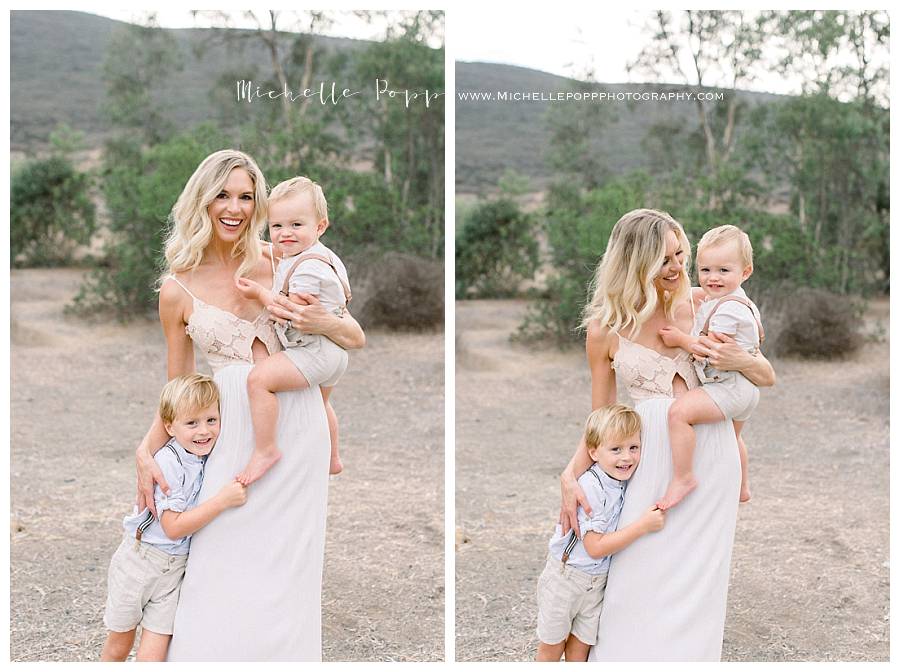 mom snuggling baby boys in field