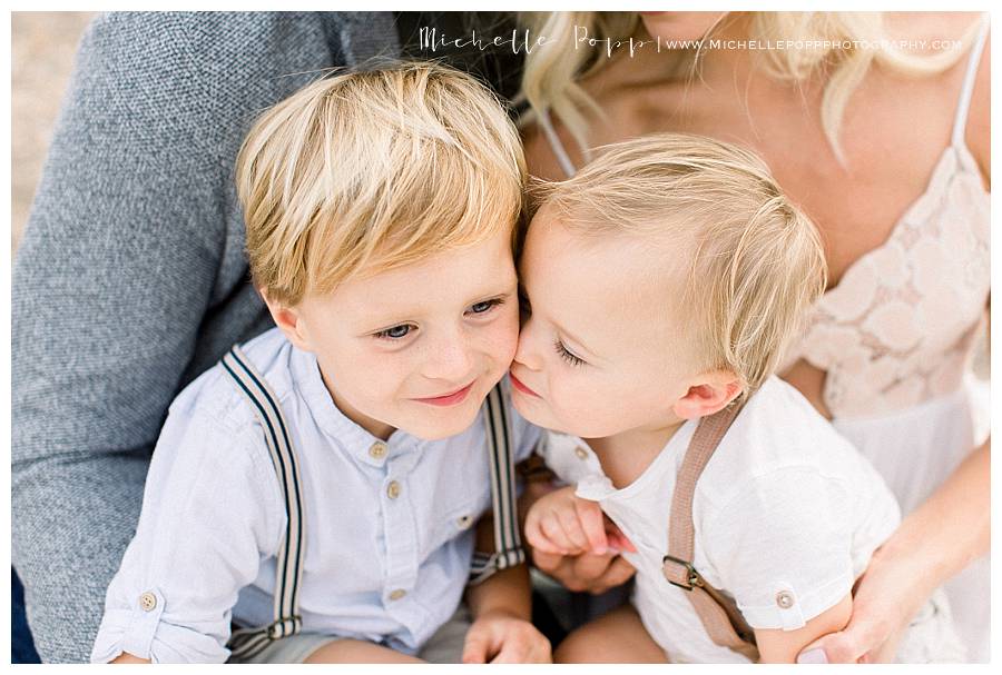 baby brother kissing older brother in trousers