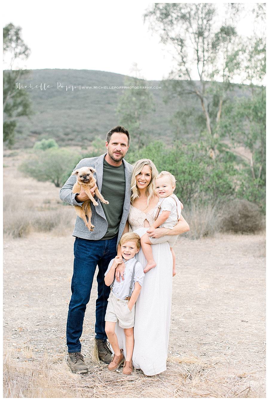 family of four with dog in field