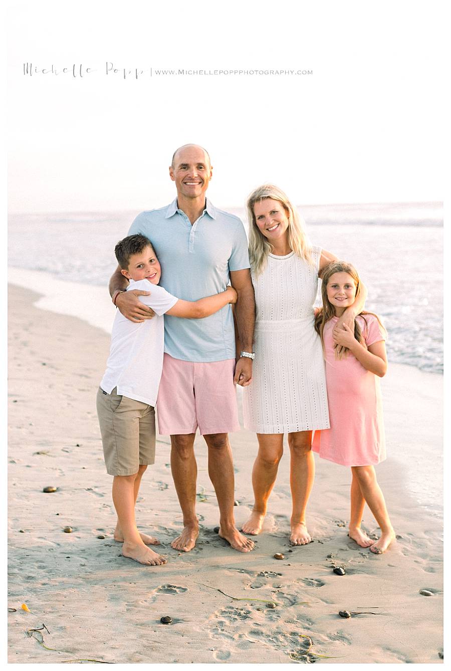 family of four hugging at beach