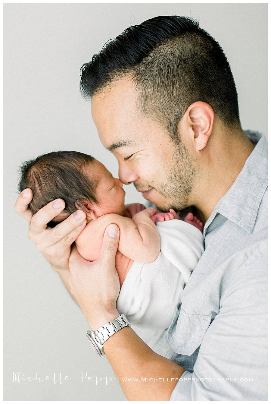 dad touching noses with newborn baby