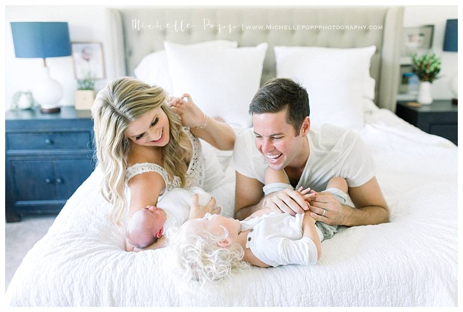 family snuggling kids on white bed