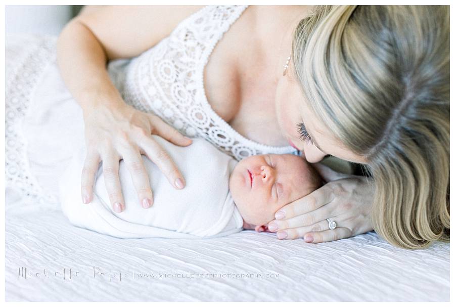 mom kissing newborn girl on head