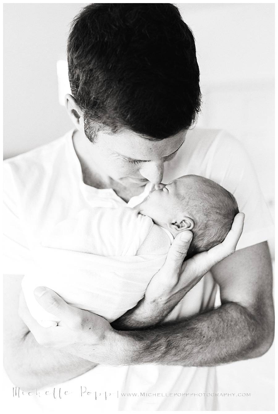 dad holding newborn girl in arms