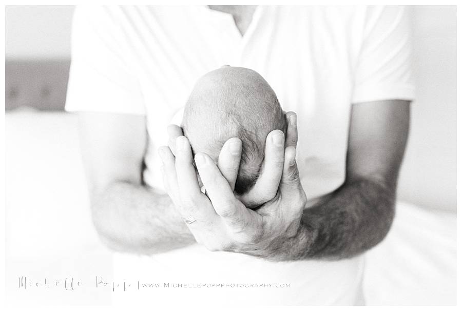 mans fingers holding newborn head