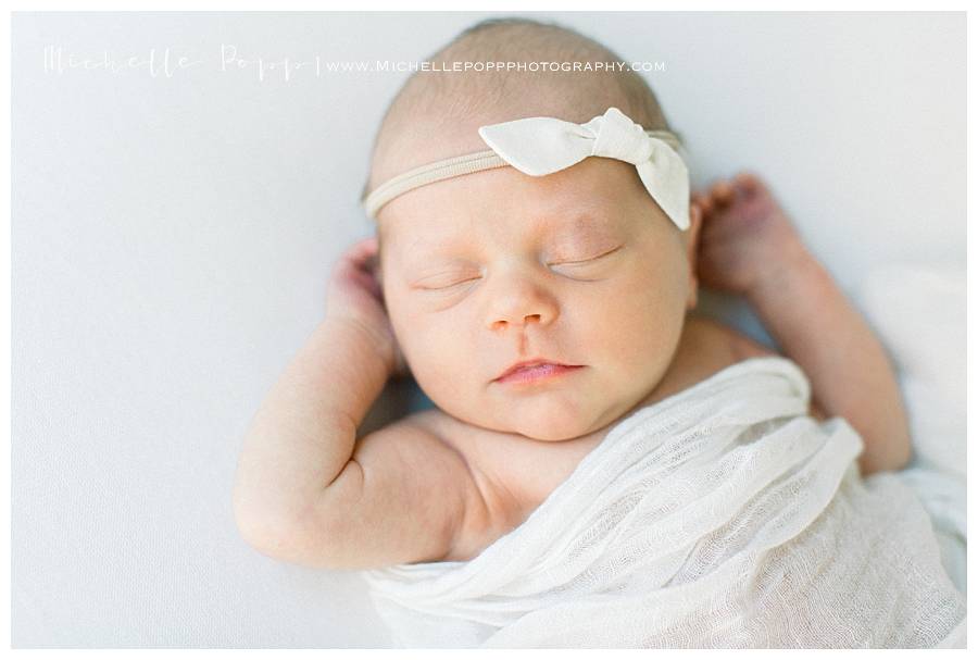 newborn girl sleeping with arms up