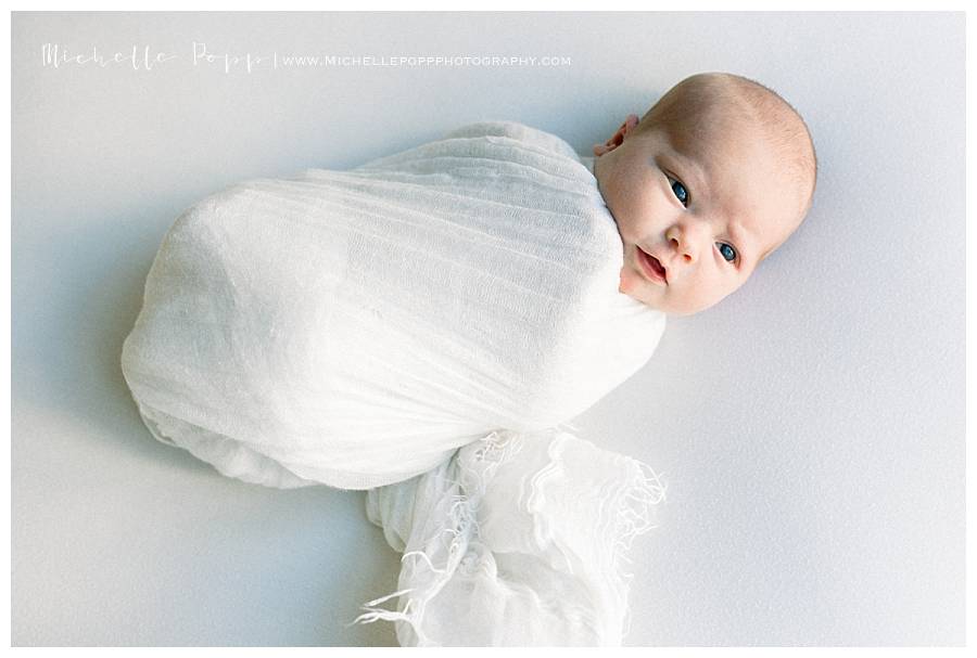 newborn in white swaddle