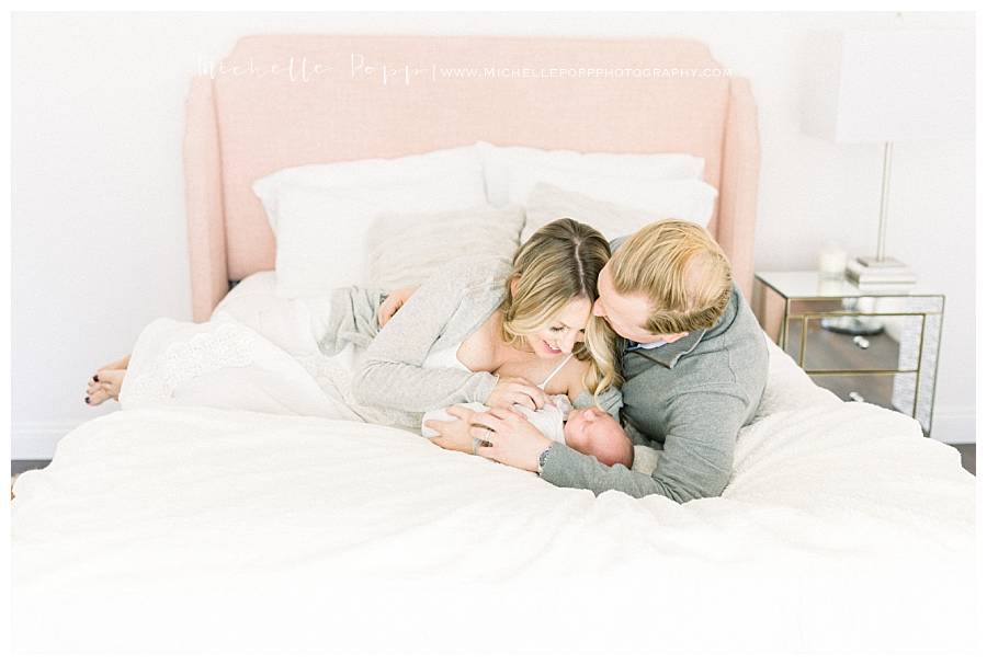 family snuggling on bed with newborn