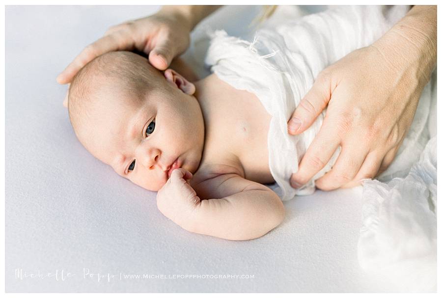 newborn baby opening eyes on bed