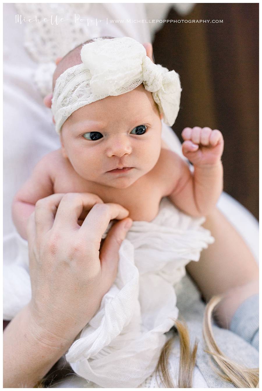 newborn baby girl in bow with eyes open