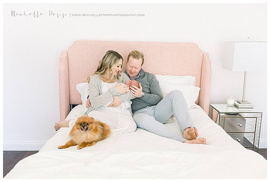 happy new parents with dog and infant on bed