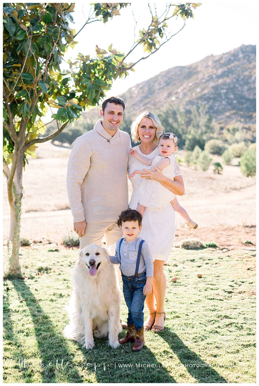 family of four in field with dog