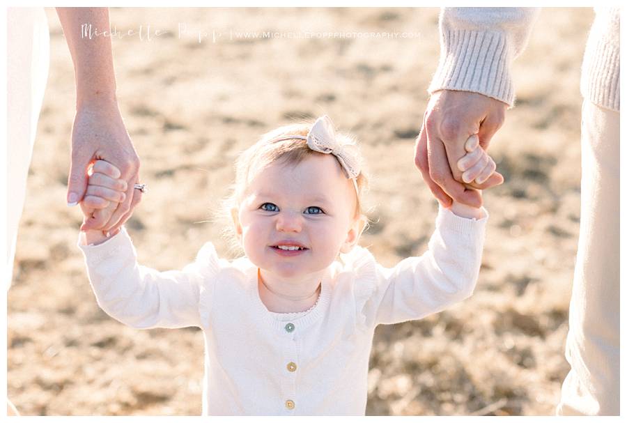 little girl holding parents hands and smiling