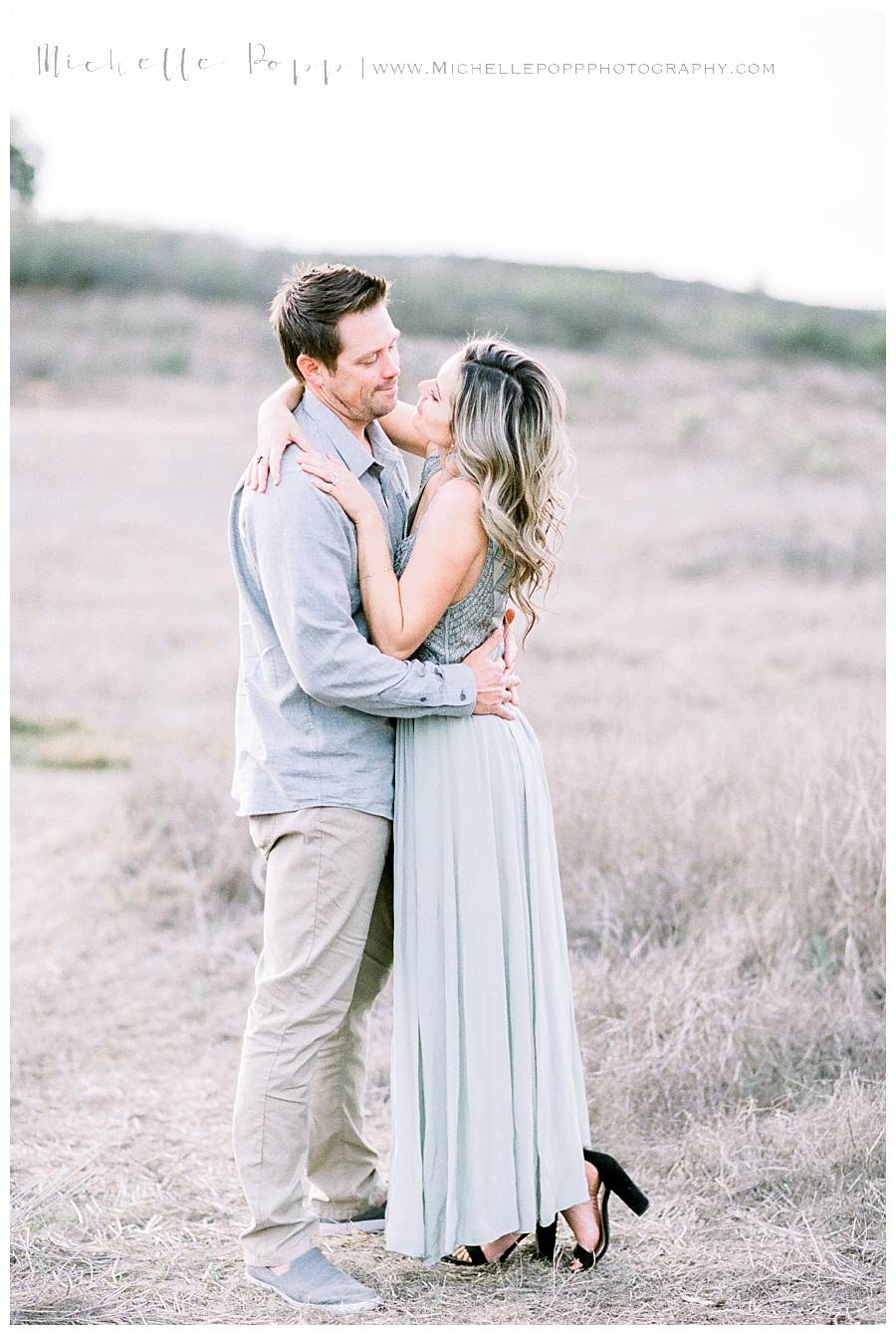 man and woman holding each other close in field