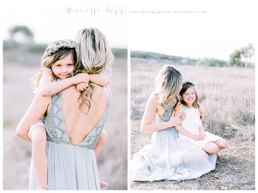 mom snuggling baby girl in field