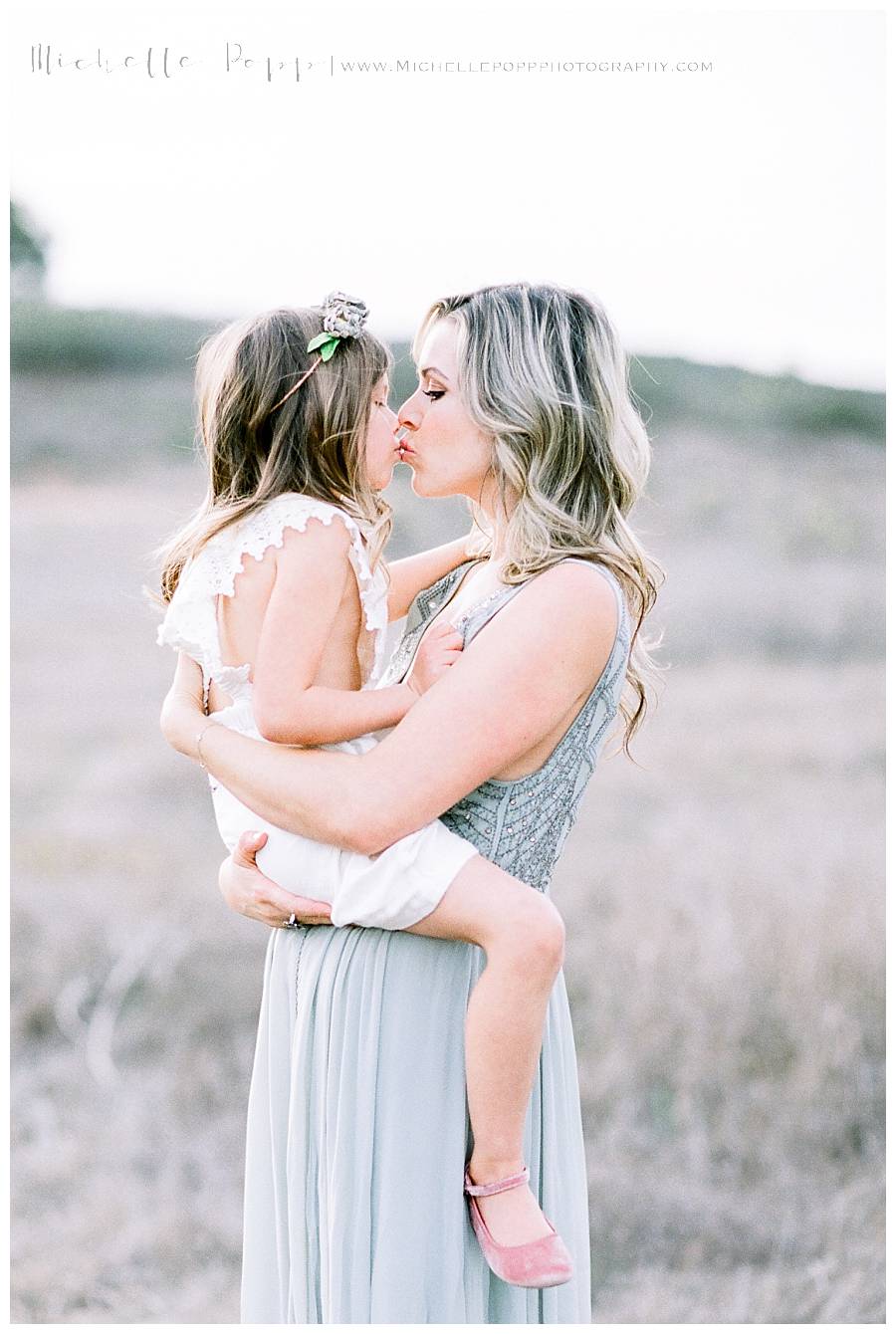 mom holding daughter and kissing her