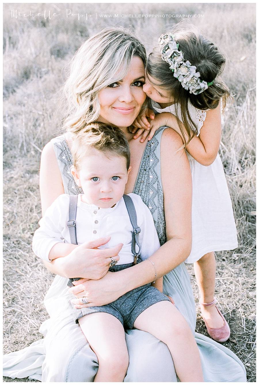 mom sitting in field with two children