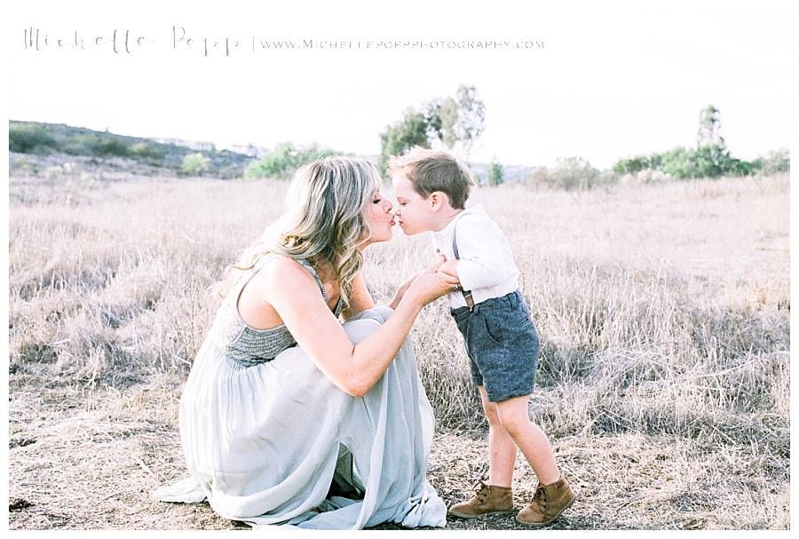 mom and son holding hands and kissing in field