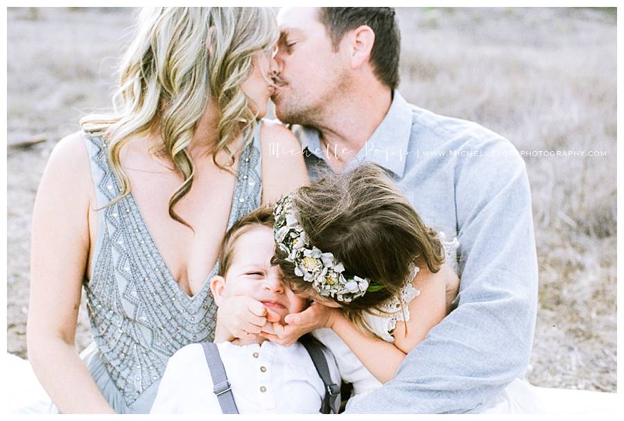 mom and dad kissing while son and daughter kiss