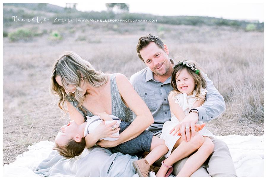 family sitting in field and laughing