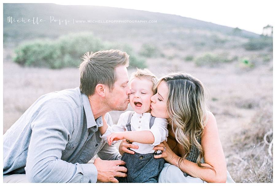 mom and dad kissing baby boy on cheeks